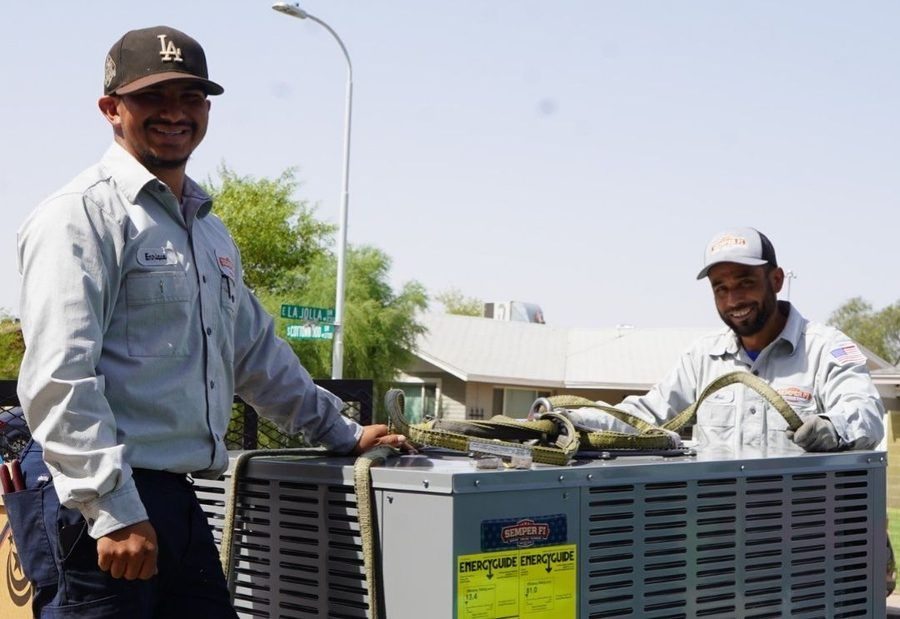 Two HVAC techs standing in front of HVAC unit during home comfort visit.