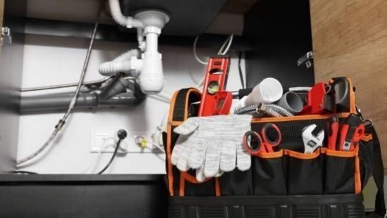 Plumbing tools and open underside of sink.