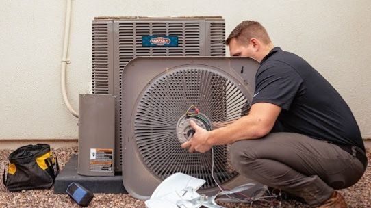 HVAC tech pulling apart and repairing an AC unit.