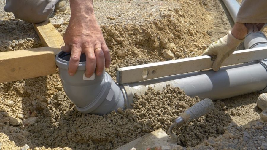 Exposed sewerline pipe in underground trench.