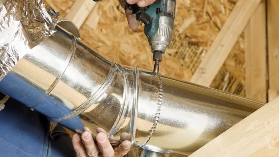 Technician installing galvanized HVAC ductwork in an attic to improve airflow and home comfort.