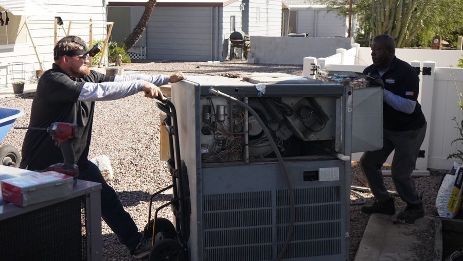 Professional HVAC technician servicing an outdoor packaged heating and cooling unit at a residential home in Phoenix.