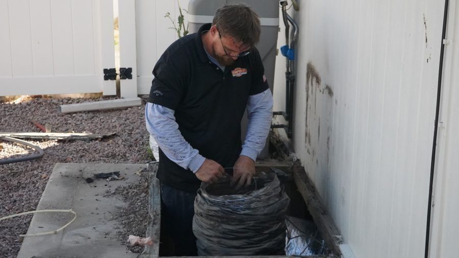 HVAC technician preparing flexible air ducting during ductwork installation or replacement at a residential home.