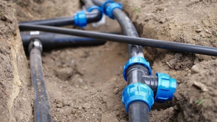 Exposed water lines in hole in ground.