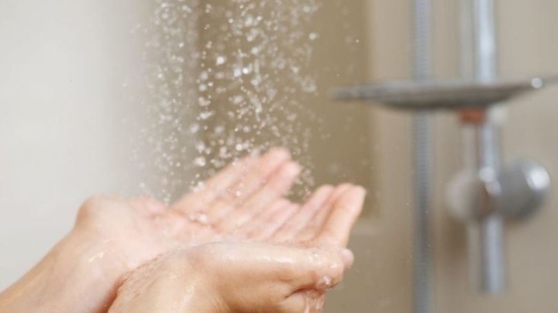 hands out stretched underneath faucet benefited by a water softener.