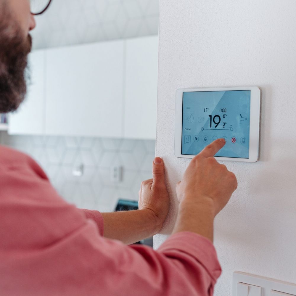 Man,using,smart,thermostat,,adjusting,,lowering,heating,temperature,at,home.